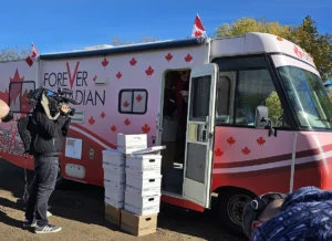 Media filming volunteers unloading petition boxes from a Forever Canadian campaign bus.