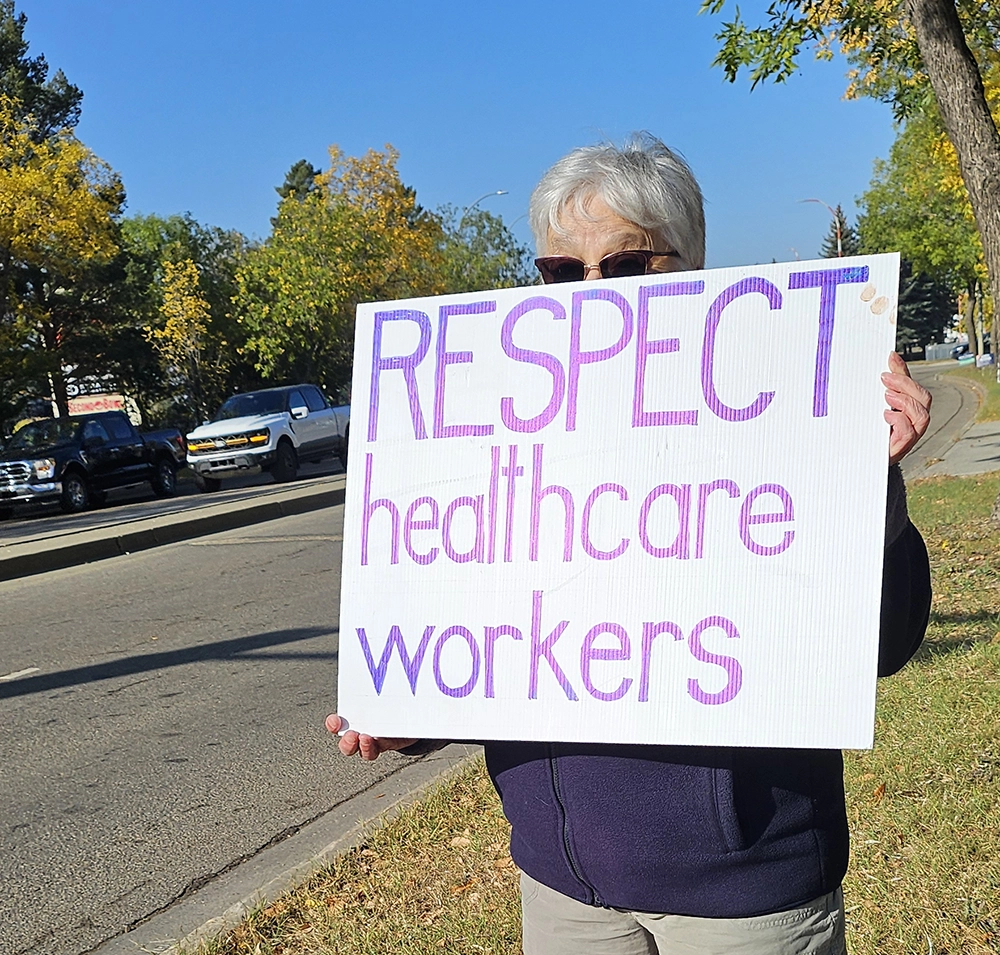 Person holding sign reading “Respect healthcare workers” at roadside rally