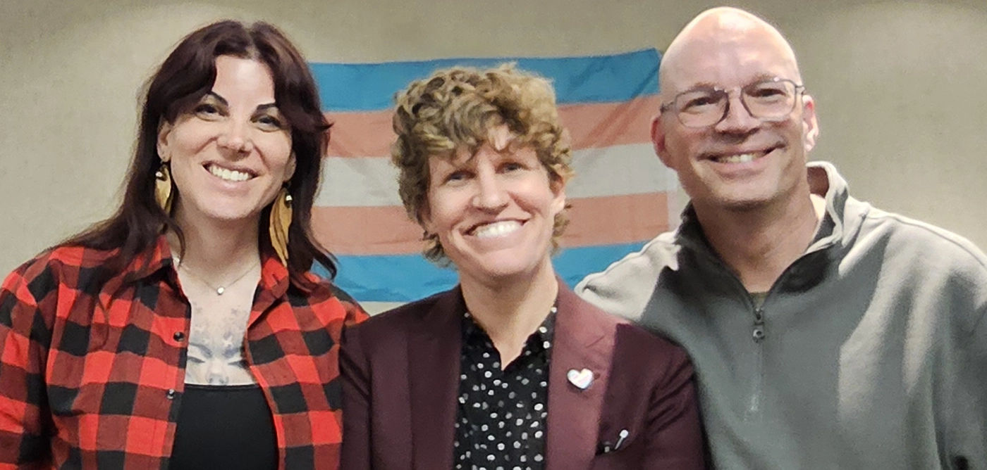 Three speakers at a St. Albert community dialogue with a trans pride flag backdrop