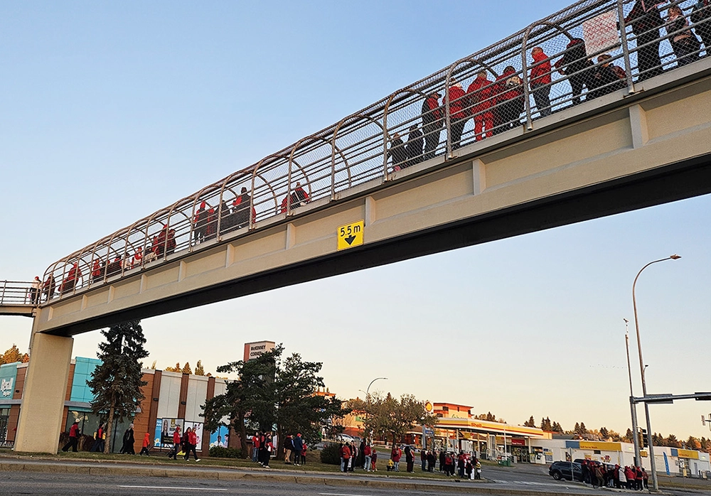 People gathered on pedestrian overpass and roadside during community rally supporting teachers in St.Albert