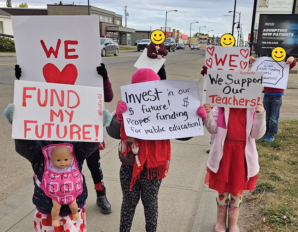 Children holding signs supporting public education at roadside protest