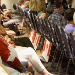 Attendees Forever Canadian Town Hall , lawn signs placed by chairs